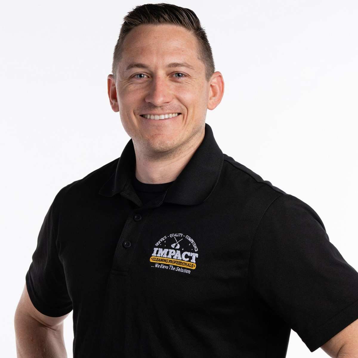 A headshot of Taylor Riley - a man wearing a black polo shirt smiling into the camera