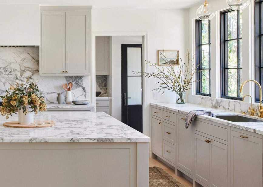 An example of how much does it cost to have kitchen cabinets painted showing a large kitchen with cream cabinets and a marble worktop