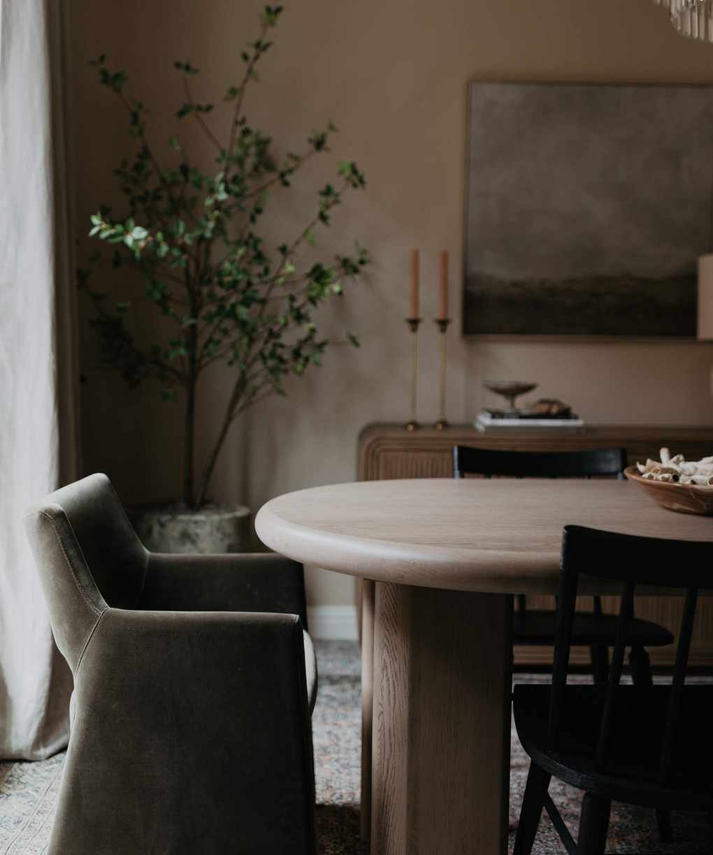 A beige-colored dining room with a tree in the corner.