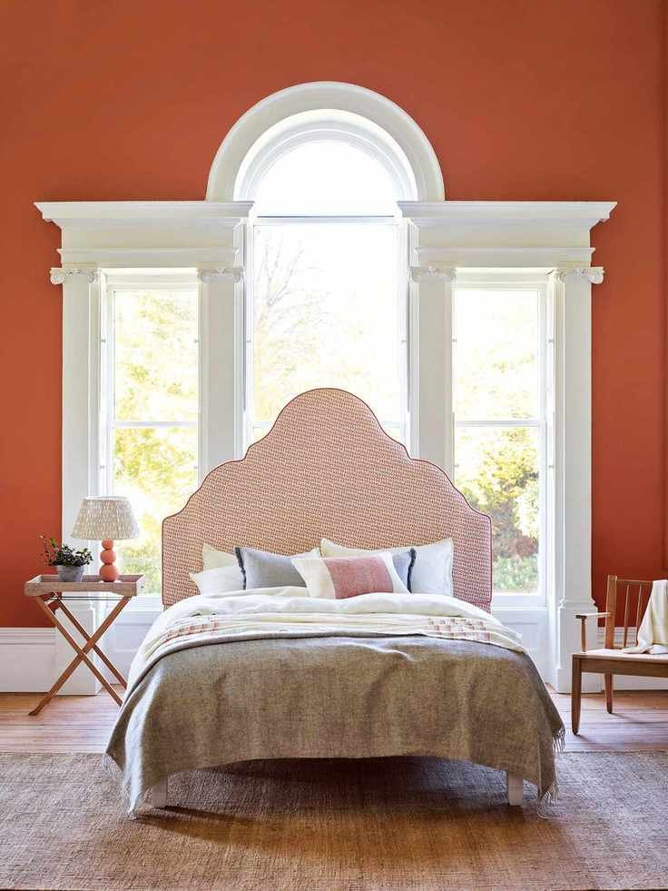 Bedroom with terracotta painted walls in Burnt Sienna and Clemmie headboard from a decor brand