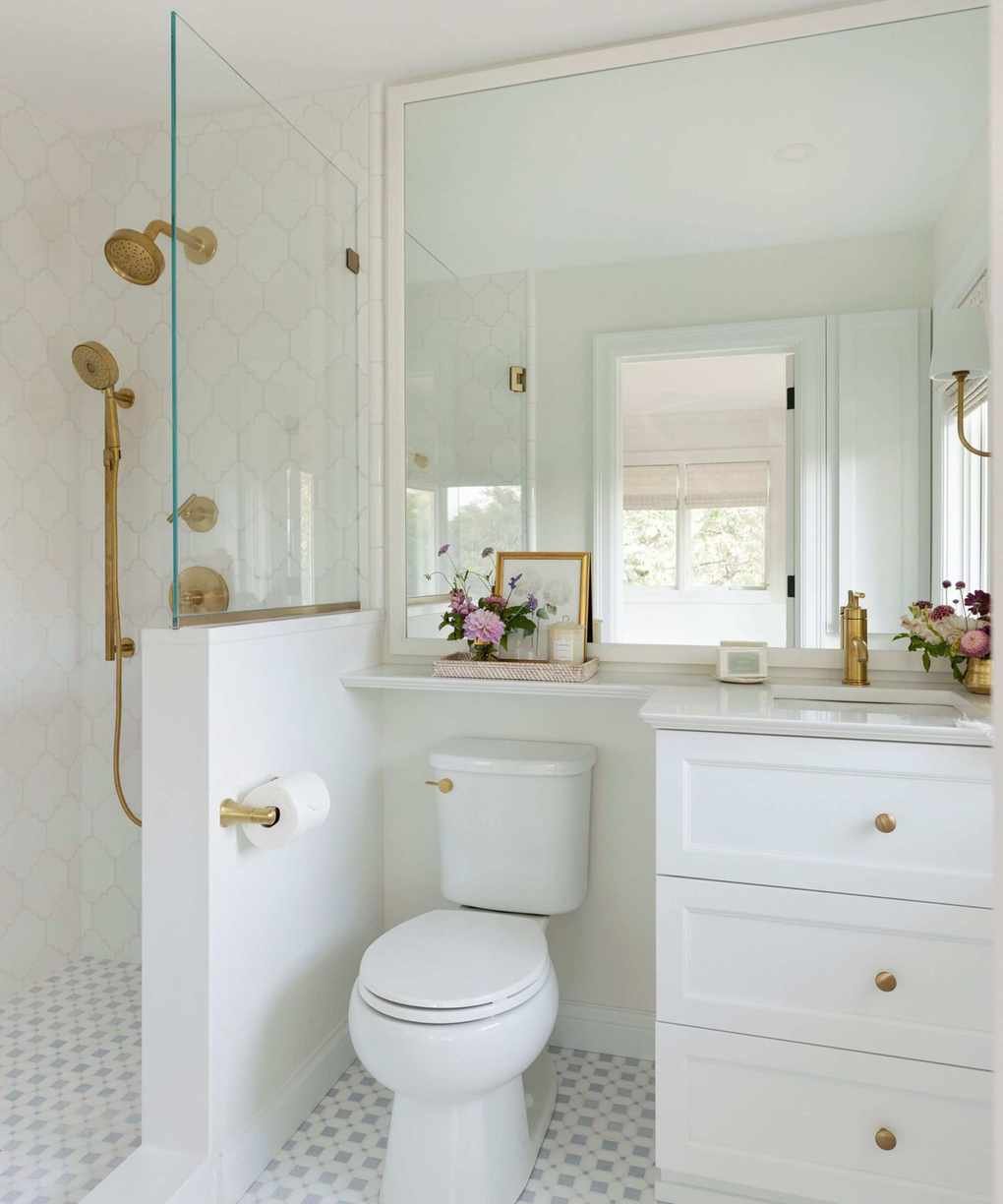 A guest bathroom with white walls and brass hardware
