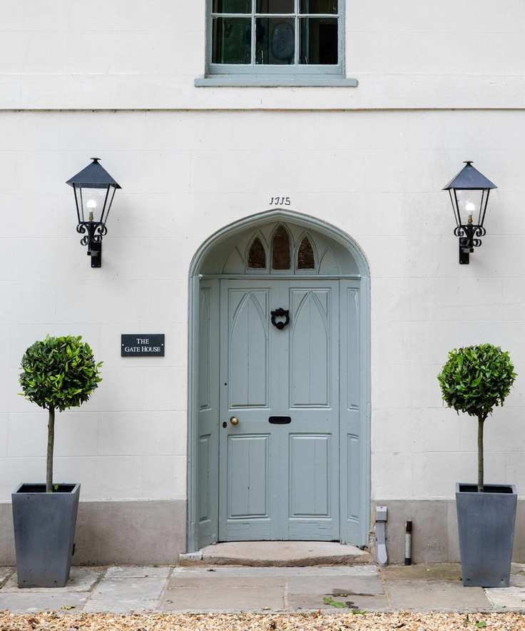 white stone house with blue front door and bay trees