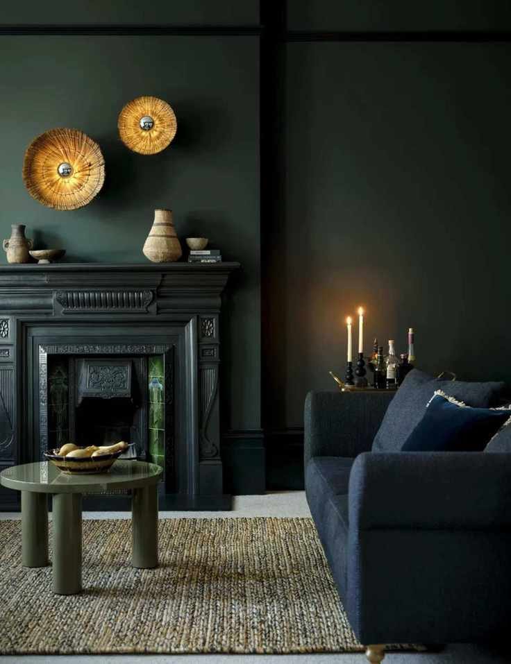 Moody dark colored living room with dark blue sofa, green shiny coffee table, gold wall art and fireplace