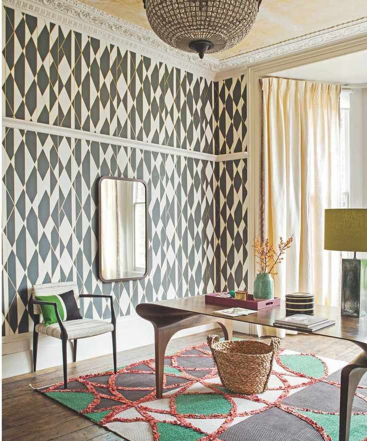 Patterned black and white wallpaper with chandelier and vibrant rug and desk