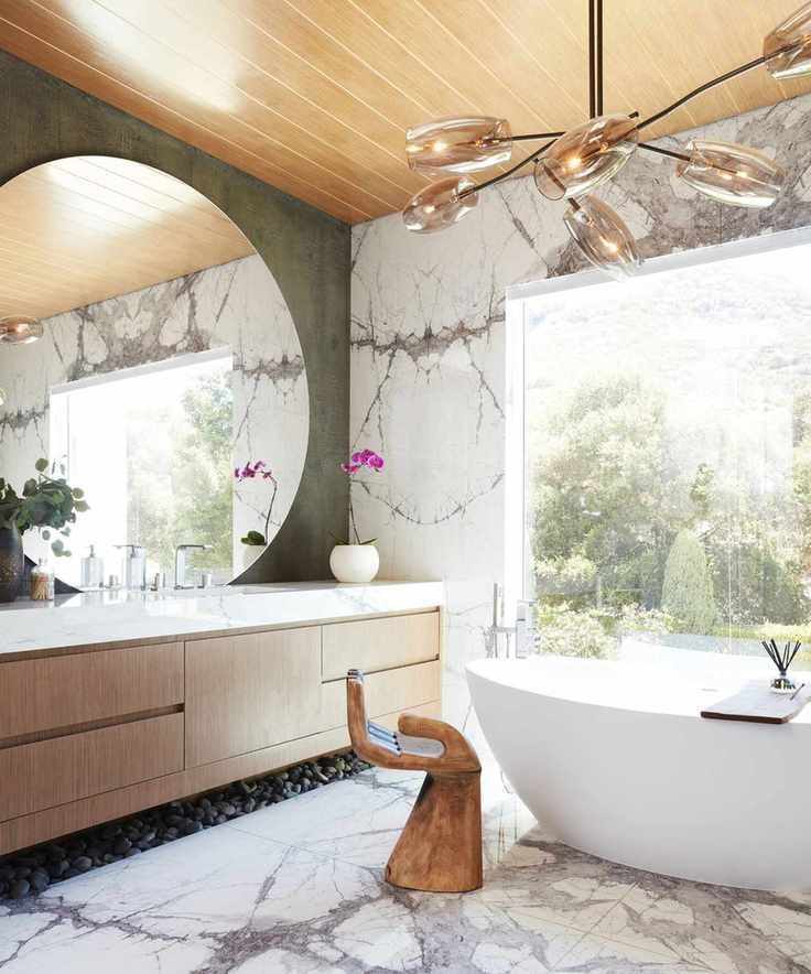 Modern bathroom with a large round mirror and marble tiles