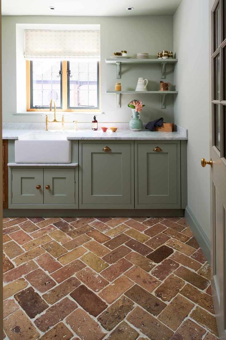 A utility room with green cabinets and a red brick floor
