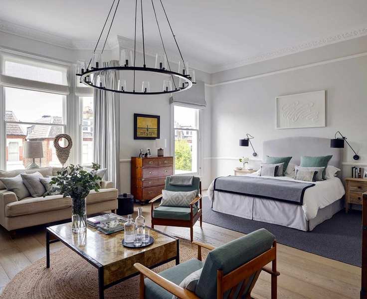 A large bedroom with grand ceiling lighting above a lounge area and white walls