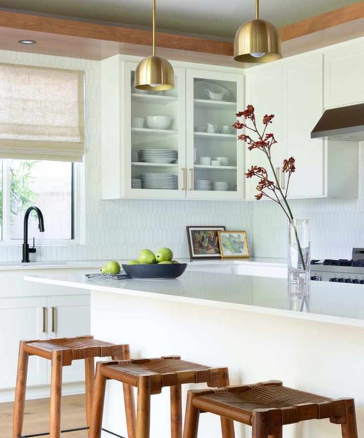 Chic white kitchen showcasing a shaped tile backsplash and wooden stools