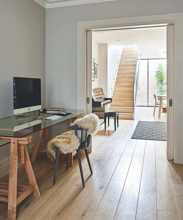A bright and airy basement with wooden flooring and a piano in the background.