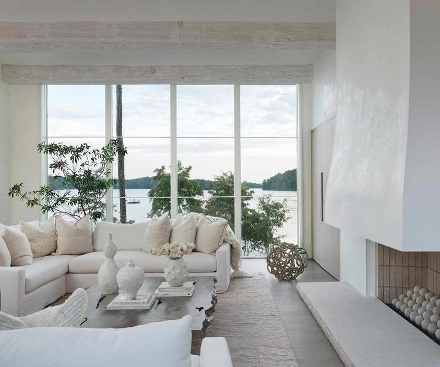 modern living room with all-white color scheme, large floor-to-ceiling windows with a view of the lake
