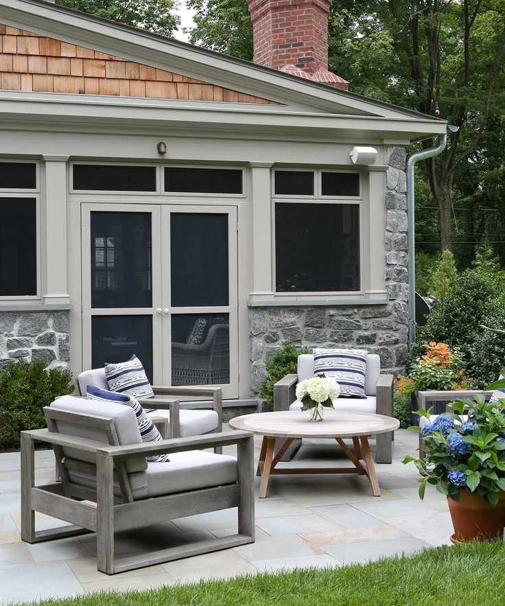 Small back yard landscaping ideas featuring a pale gray patio with gray wooden chairs around a circular coffee table, with potted hydrangeas.