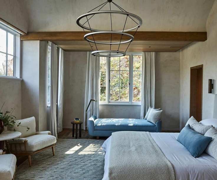 Neutral bedroom with wood beams, statement pendant light and double bed and day bed