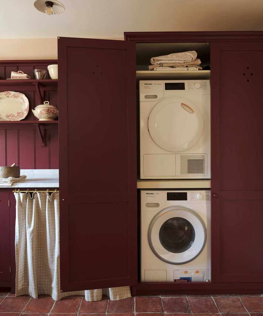 A burgundy laundry room with stacked appliances