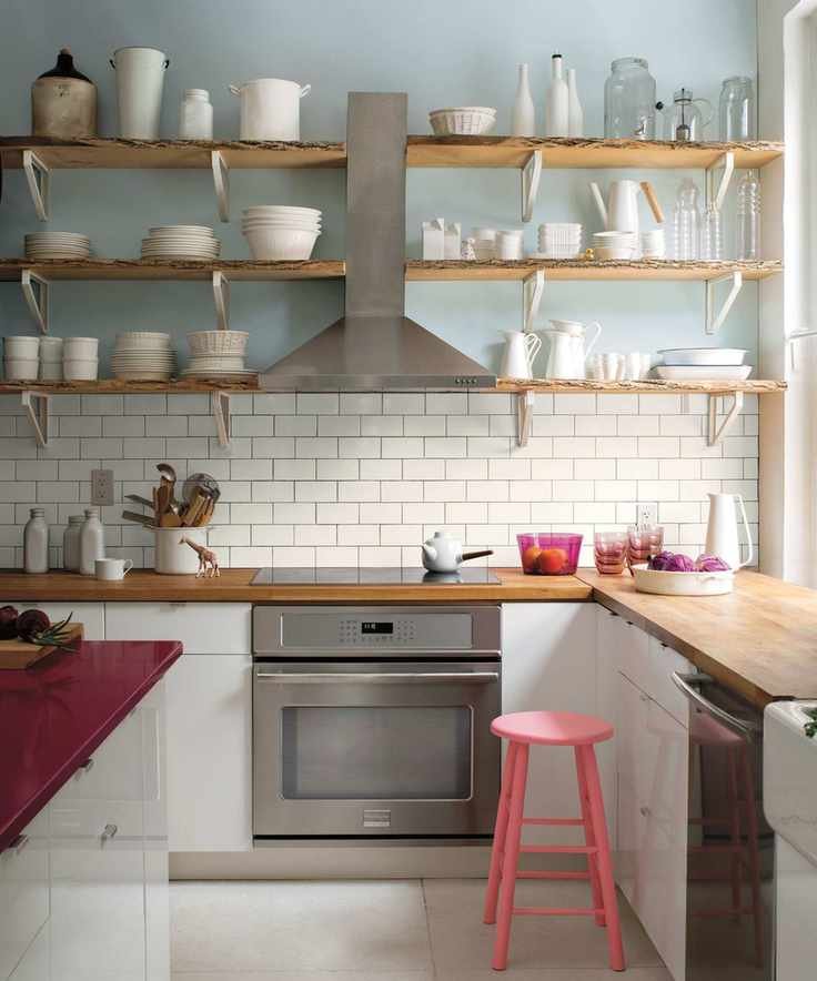 A kitchen with white cabinets, light blue walls, and wooden open shelving