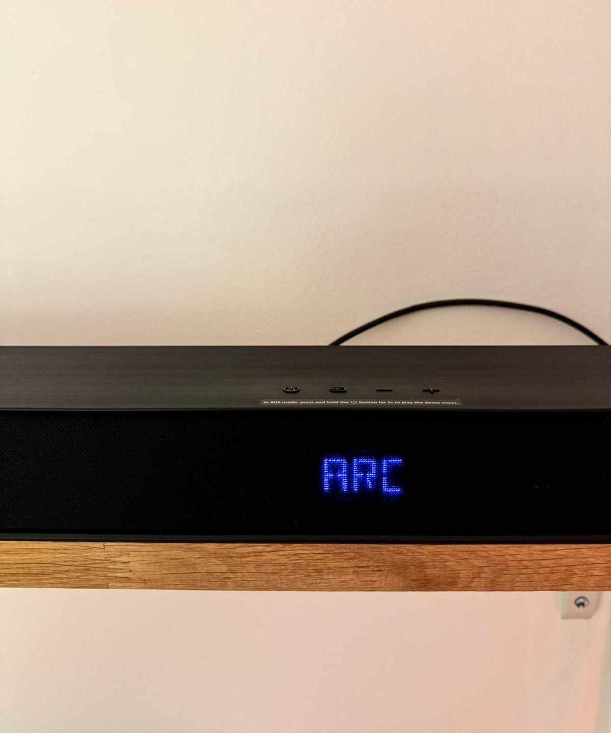 Hisense AX5140Q soundbar on wooden shelf, with blue lit-up text displaying 'ARC'