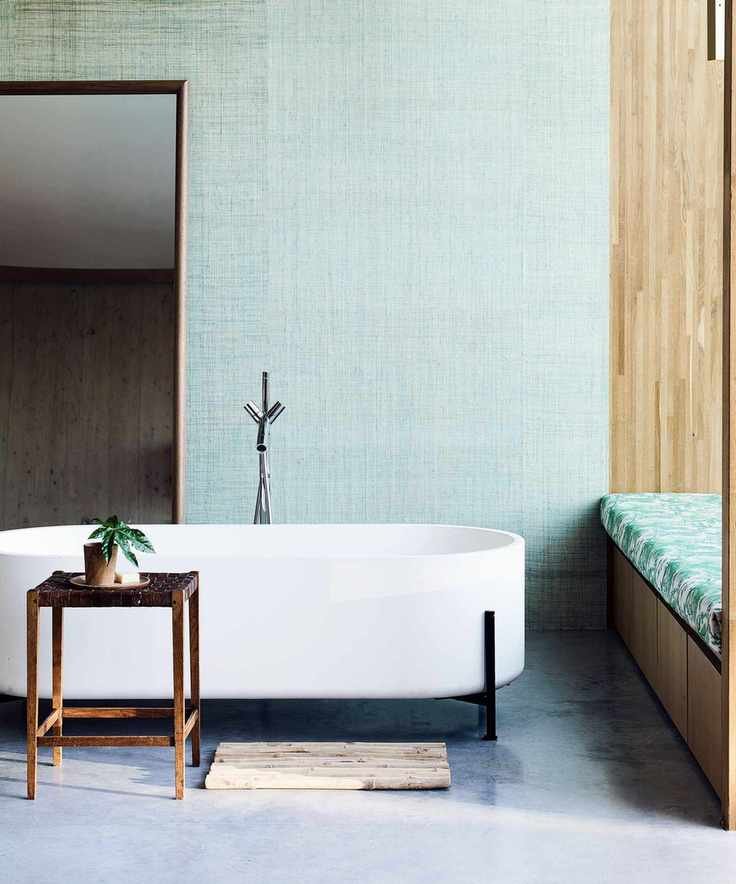 A modern white bath against a green wall