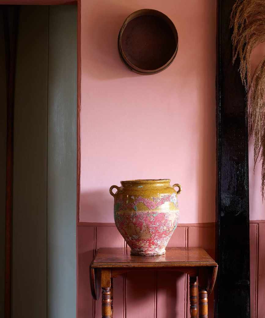 Red entryway with pink painted walls and urn on table