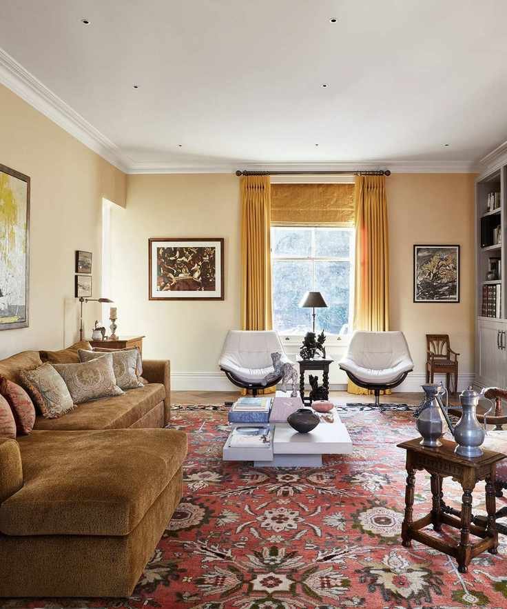 Soft yellow living room with a velvet ochre couch, yellow window treatments, and a large patterned terracotta rug with two armchairs and a contemporary coffee table sat on top