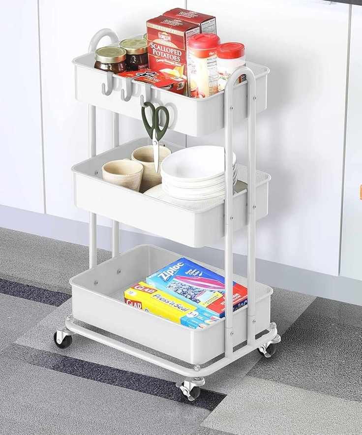 White utility rolling cart in a stylish kitchen filled with food and dishes.