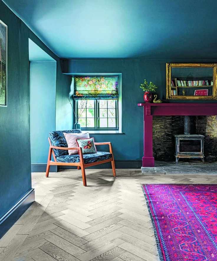 Living room with blue walls and a fireplace, featuring a lounge chair next to a pink rug
