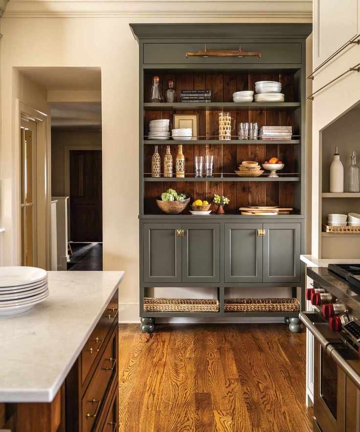A kitchen with white walls, a wooden island, and a green freestanding unit with open shelving