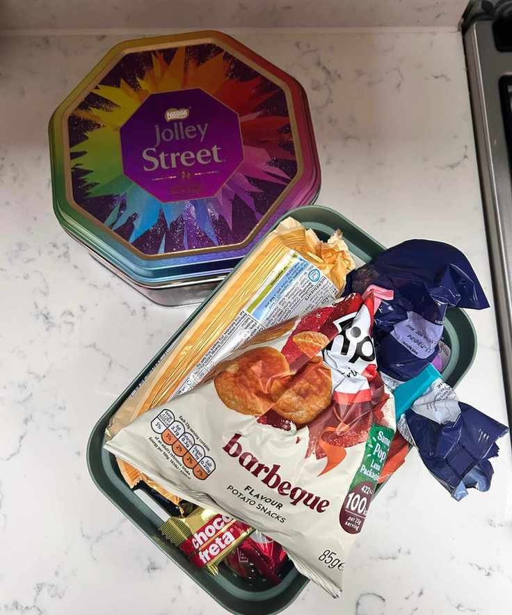 Messy snacks arranged in a green box and Quality Street tin