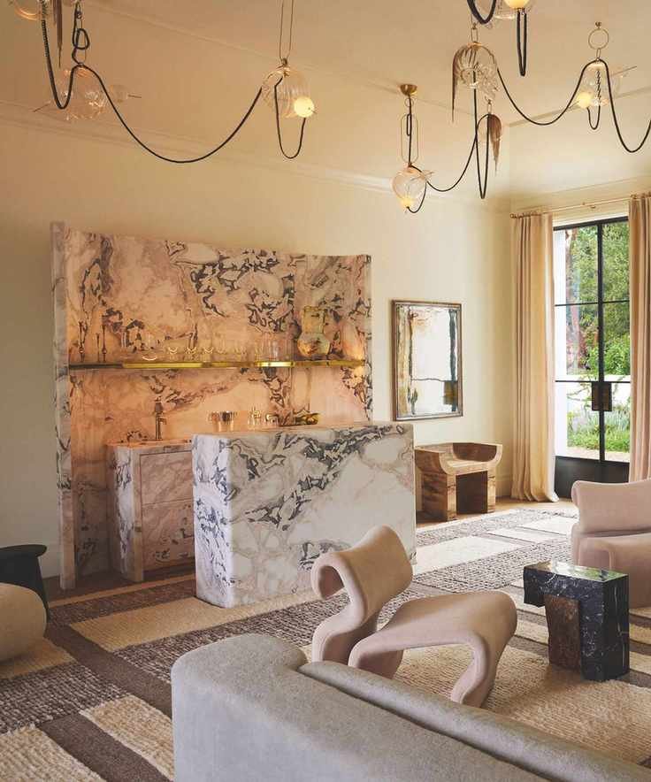 pink marble bar in corner of room with hanging pendant lights and patterned woven carpet