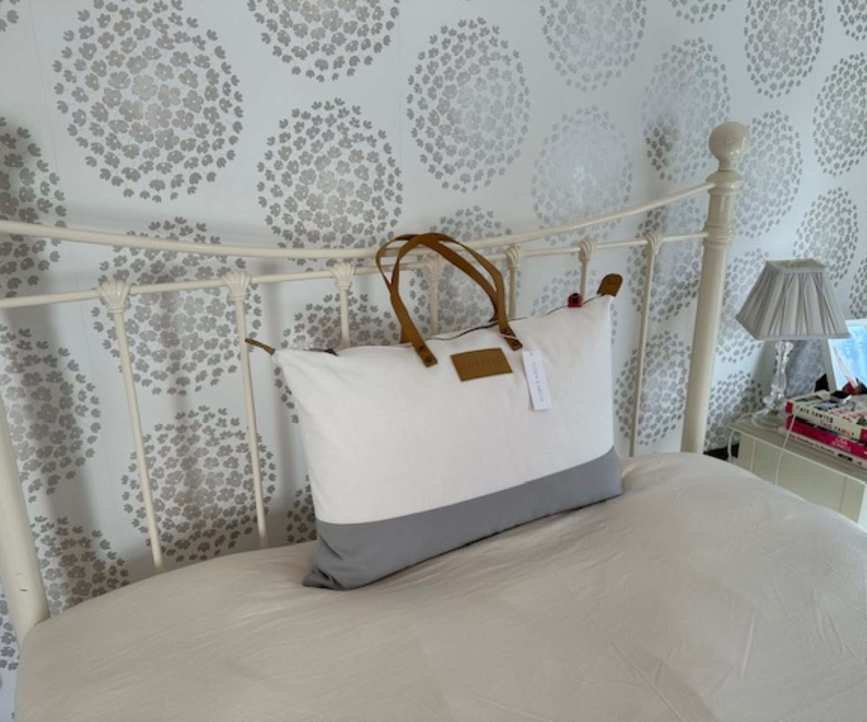 Cozy Earth Silk Pillow in a reusable tote on a bed.