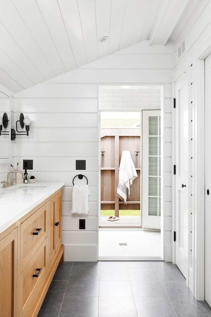 vanity unit in bathroom with view to walk through showerindoor outdoor shower in beach hut with fence and towel outside