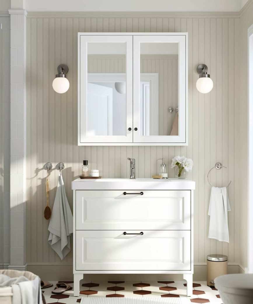 An IKEA bathroom with beige paneled walls, a white vanity, and matte black hardware
