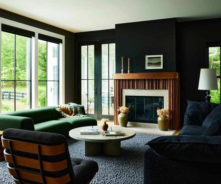modern living room with black walls and sofa, a gray rug, and a green sofa in front of sliding glass doors