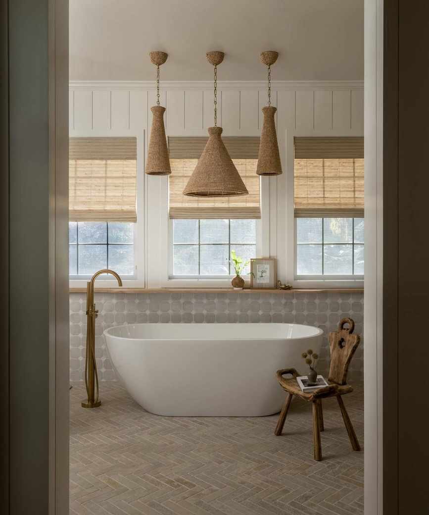 bathroom with neutral color scheme, freestanding bath, woven window blinds, and three rattan pendant lights