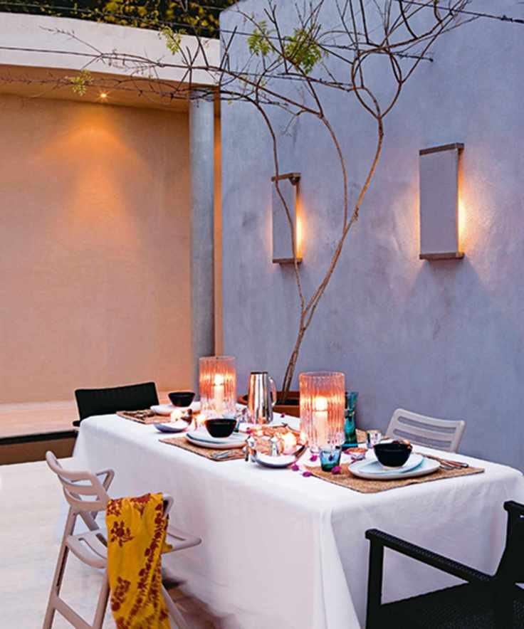 An outdoor dining scene with wall lights above
