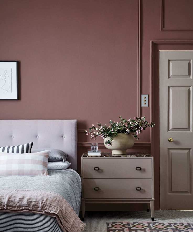 A calming bedroom with earthy pink walls and neutral furniture.