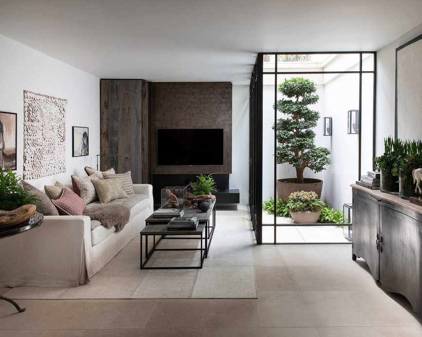 Beige living room with wooden features and greenery.