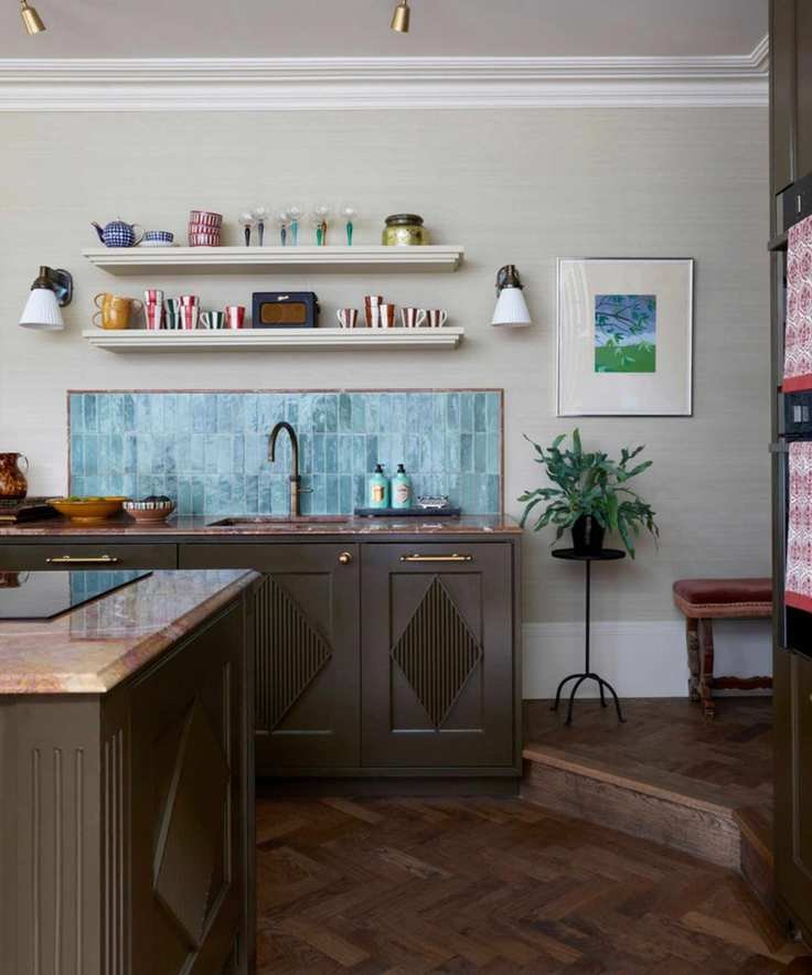 A small kitchen with warm white walls, a blue tile backsplash, and green cabinets with a textured diamond detail