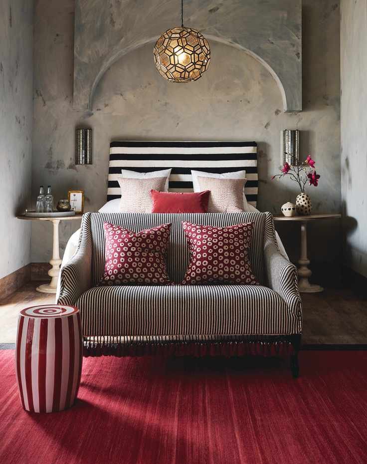 bedroom with red rug, stool, cushions, black and white headboard, black and white sofa, matching side tables