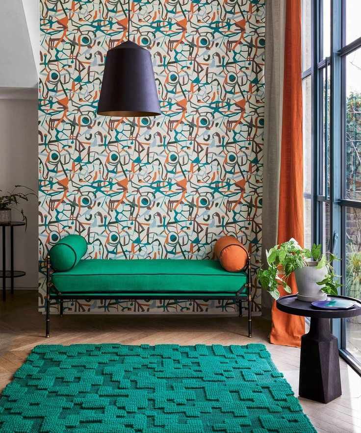 Green upholstered ottoman in front of abstract wallpaper