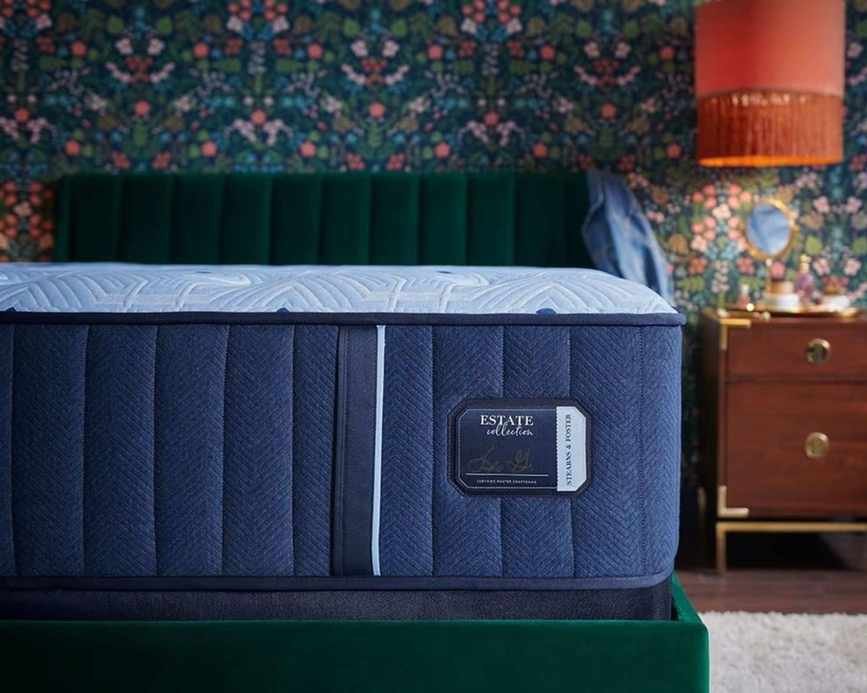 A blue Stearns & Foster Estate Mattress on a green velvet bed.