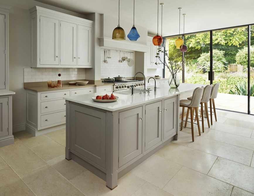 A neutral kitchen with colorful glass pendants and large glass doors.