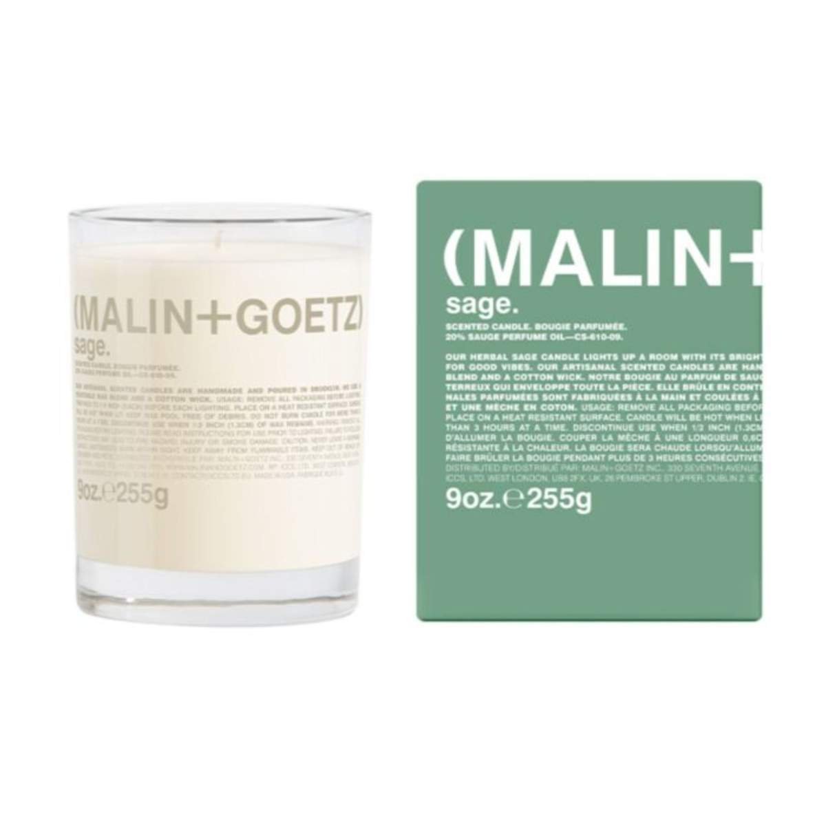 A white glass candle next to a green cardboard candle packaging box