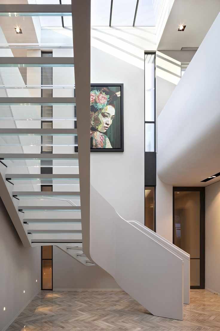 View of staircase with glass treads from underneath, parquet floor and neutral walls