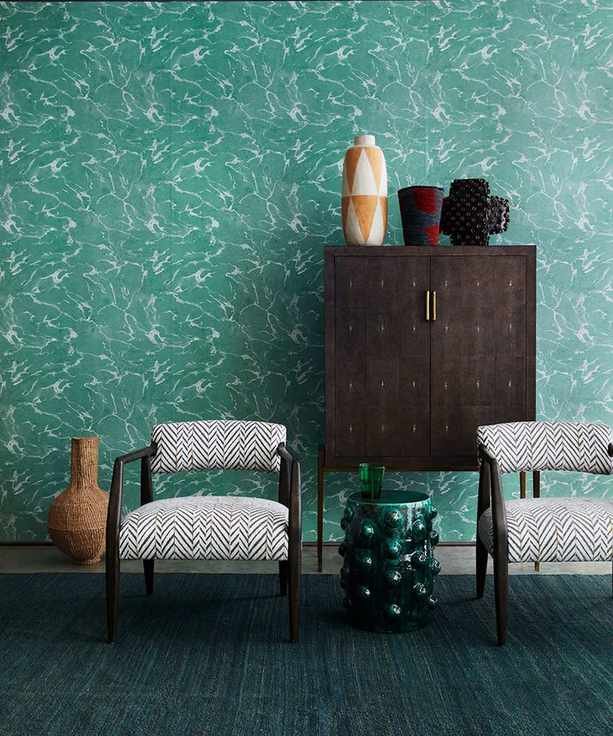 Living room picture showing deep green wallpaper with patterned chairs in front.