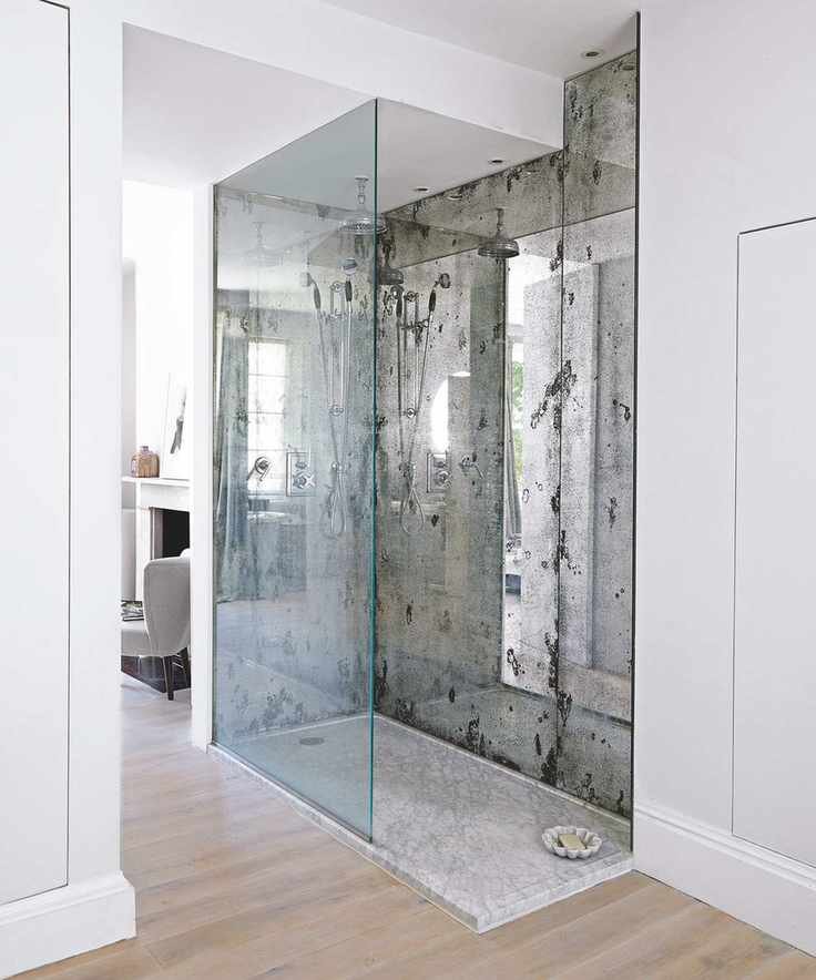 Walk-in shower with glass backsplash and mirrored walls.