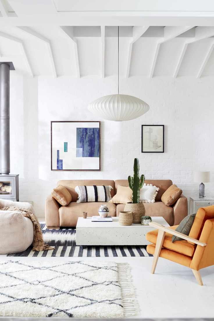 white living room with beams, sofa, armchair and rugs, pictures on wall