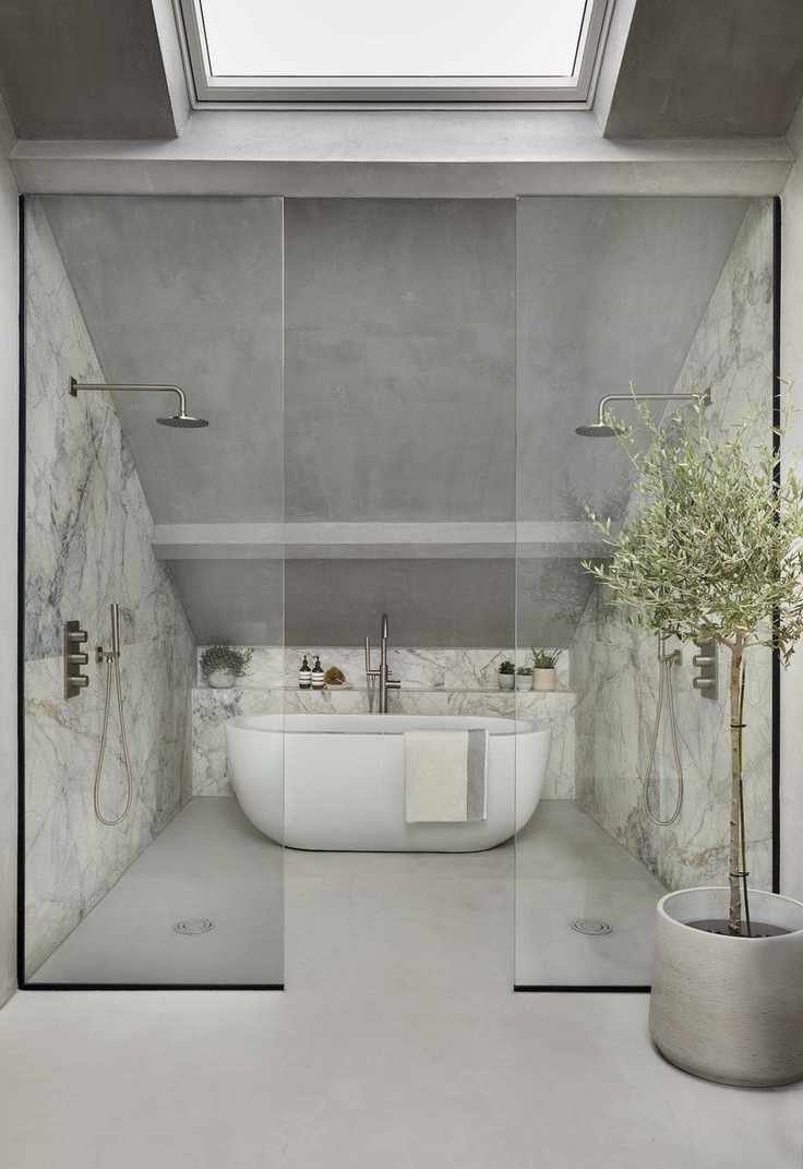 A loft bathroom featuring gray walls, glass doors, and marble with chrome fixtures