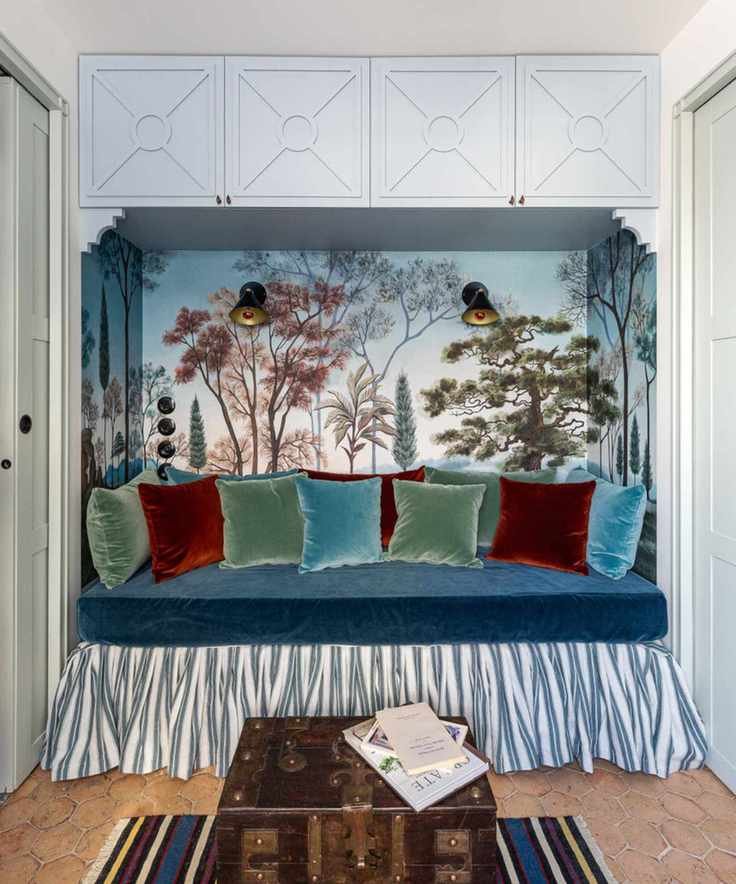 Daybed with blue cabinetry, wall mural, velvet cushions and tiled floor