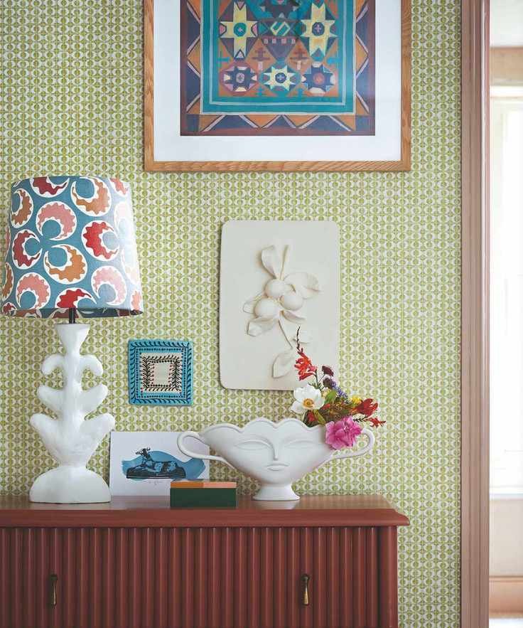 A bright and colorful room with patterned wallpaper and a vase of flowers