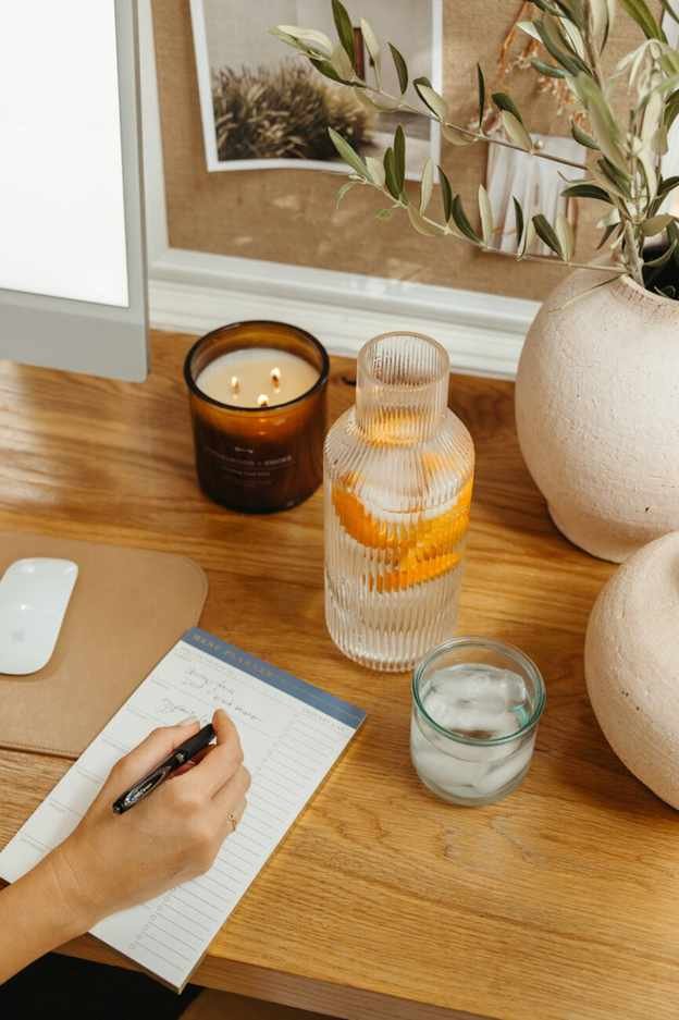 Woman writing plant-based meal prep on weekly menu planner.