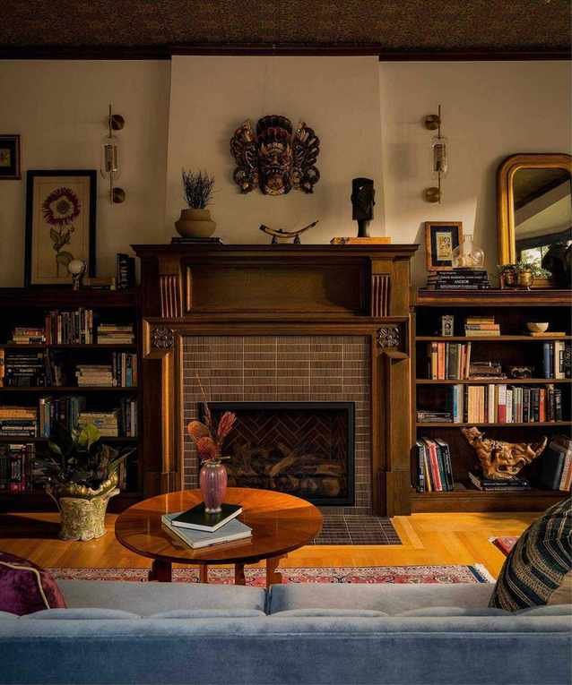 a moody home library with a wallpapered ceiling and original tudor fireplace